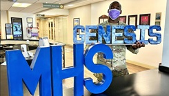 A man holds an MHS GENESIS sign.