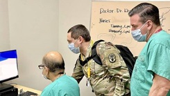 Military personnel looking at a computer