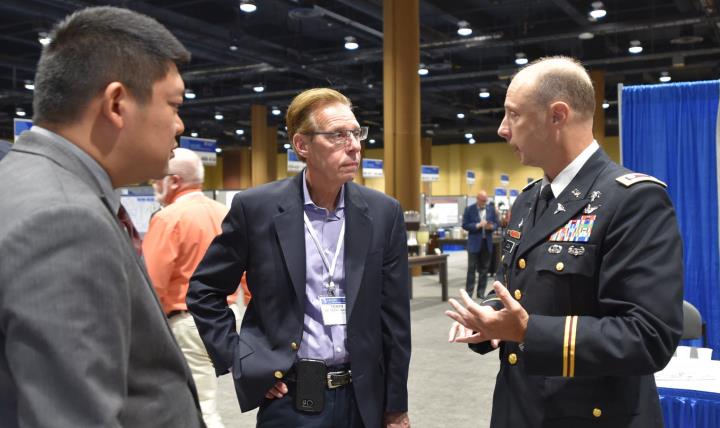 Dr. Terry Rauch (center), acting deputy assistant secretary of Defense for Health Readiness Policy and Oversight, chats with fellow attendees of the Military Health System Research Symposium, just completed in Kissimmee, Florida. (Photo: Greg Pugh, U.S. Army Medical Materiel Agency)