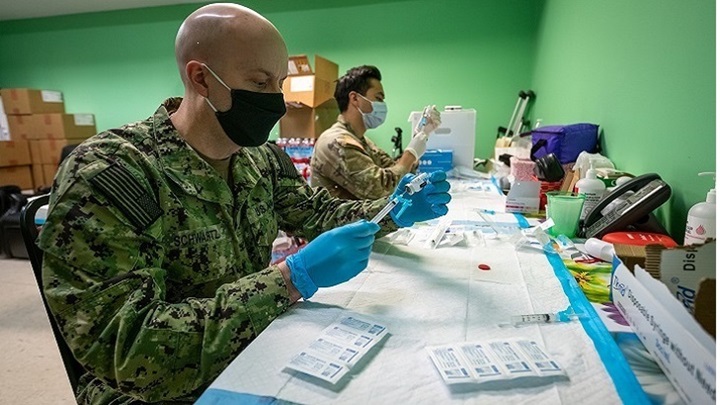 Image of Military personnel wearing face mask getting people ready for the COVID-19 vaccine.