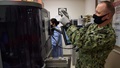 Military health personnel wearing a face mask using a blood analyzer machine