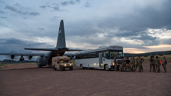 Airmen and soldiers from multiple units treat a patient in front of an ambulance bus parked behind a C-130 Hercules aircraft during Exercise Mountain Medic 23 in Fort Carson, Colorado, on Aug. 16, 2023. The joint-service team practiced offloading patients from each ground medical transport vehicle into the cargo bay of the aircraft while its engines were running. (Photo: U.S. Air Force Tech. Sgt. Justin Norton)
