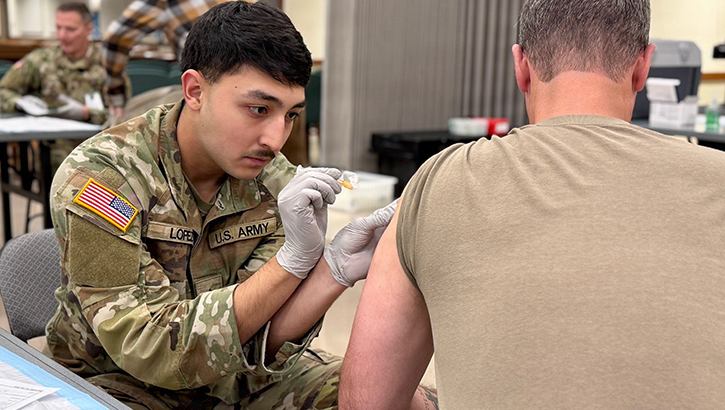 Munson Army Health Center Combat Medic Specialist Pfc. Antonio Lopez administers a seasonal influenza vaccine to a service member at a walk-in community flu-shot event