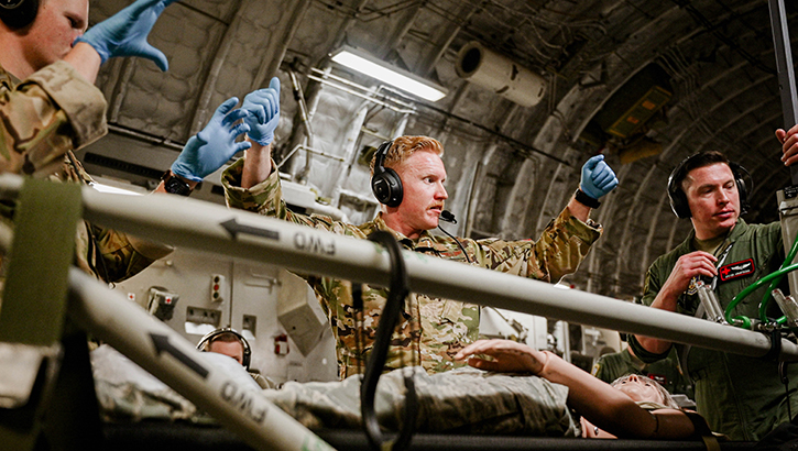 U.S. Air Force Capt. Chris Bennett, middle, a flight nurse with the 908th Aeromedical Evacuation Squadron, prepares to demonstrate a medical procedure on a simulated patient on Dec. 8, 2023, during a training flight from Maxwell Air Force Base, Alabama, to St. Croix, U.S. Virgin Islands.  (Photo by U.S. Air Force Senior Airman Juliana Todd)