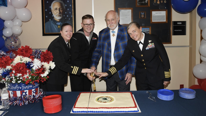 military personnel pose for picture with cake
