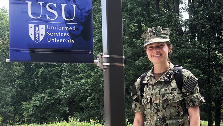 Military soldier standing next to a USU flag