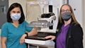 Mammography technicians standing next to a medical machine
