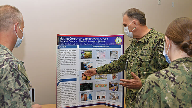 Military personnel inspecting a process improvement poster