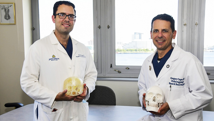 Two medical personnel holding a skull