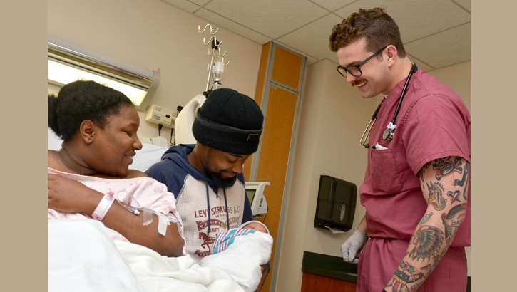 Navy Hospital Corpsman 3rd Class Tommy Baker checks on Navy Logistics Specialist Seaman Tabernesha Victrum and Romeo Taylor as they hold their newborn daughter at Naval Hospital Jacksonville’s Maternal Infant Unit. (U.S. Navy photo by Jacob Sippel)
