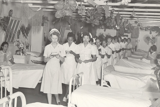 Navy nurse leading Chamorro student nurses in ward inspection (1948). The Navy became involved in the affairs on Guam in 1898. In 1911, Navy nurses established a training school in Guam to instruct Chamorro women in health and hygiene. (BUMED archives)