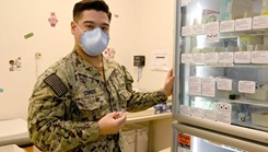 Hospitalman Hector Conde standing in front of a immunization office's refrigeration