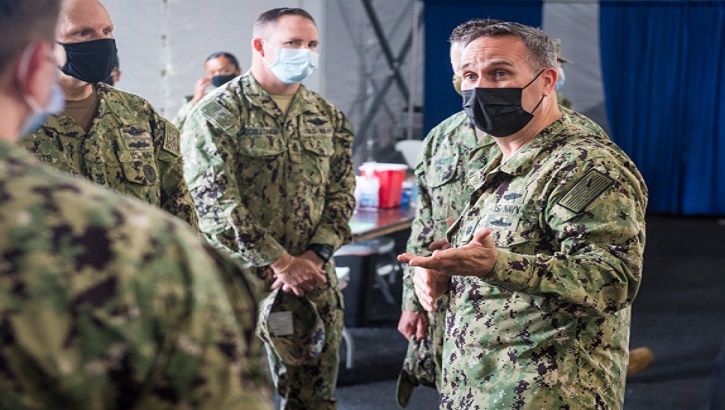 Military health personnel wearing face mask discussing the COVID-19 vaccine program