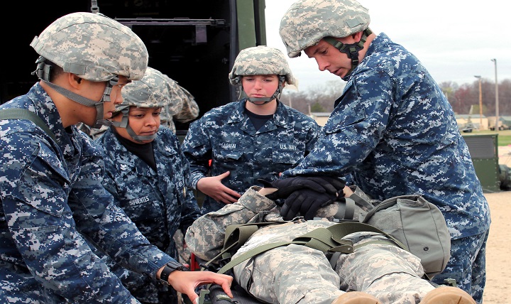 A Navy doctor and Corpsmen treat a soldier in a medical exercise. 