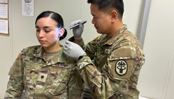 Munson Army Health Center Soldier Spc. Chaiyaporn Charoenput examines fellow Munson Soldier Spc. Dalilah Wells’ ear during a practical exercise