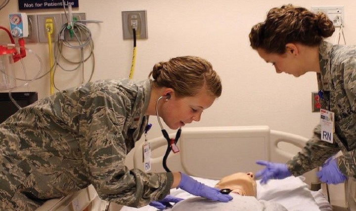 Two Air Force residency nurses practice patient care on a simulated patient. 