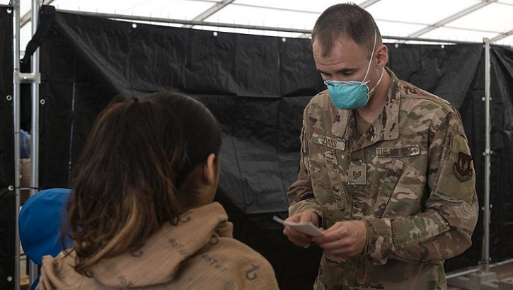 An Airman assists an evacuee during a measles, mumps and rubella vaccination program