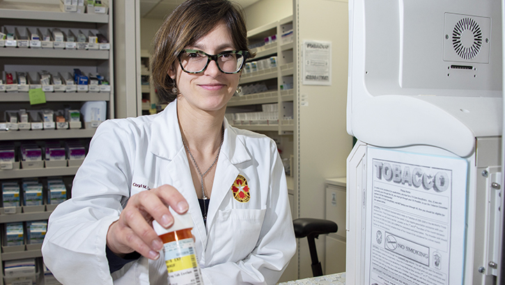 Image of Pharmacist holding out prescription bottle. Click to open a larger version of the image.