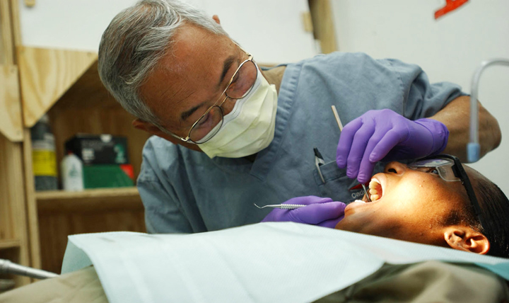 Army Colonel Richard Asami, a staff dentist for the 34th Infantry Division, cleans the teeth of Army Sgt. 1st Class Denise White-Phillips. During routine dental exams and cleanings like this one, cases of oral cancer can be discovered. (U.S. Army photo by Sgt. Spencer Case)
