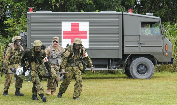 Japan Ground Self-Defense Force medics carry a casualty from an ambulance to a JGSDF helicopter while a U.S. Army medic calls directions during a bilateral medical training exercise. 