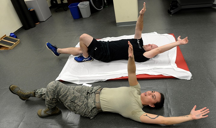 Air Force Staff Sgt. Amber Coley (bottom), a 4th Medical Operations Squadron physical therapy technician, demonstrates an exercise for Tech. Sgt. Jared Rhynehart, a 4th Aircraft Maintenance Squadron lead support team member, during a rehabilitation session. The physical therapists assign several different exercises per session with difficulty dependent on the patient’s injury or pain area. (U.S. Air Force photo by Airman 1st Class Ashley Williamson)