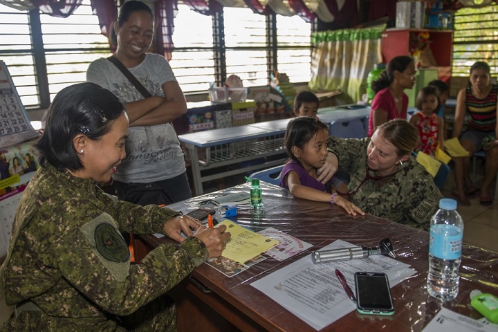 Navy Lt. Sharon Hoff (right) listens to a patient’s heartbeat as Philippine Army Capt. Glorife Saura from the Armed Forces of the Philippines Medical Corps records patient vital signs. Pacific Partnership participants and Tacloban City medical professionals worked together to provide medical and veterinary services throughout the day at Tigbao Diit Elementary School. (U.S. Navy photo by Mass Communication Specialist 1st Class Nathan Carpenter)