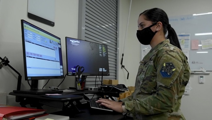 Image of Military personnel typing on a computer.