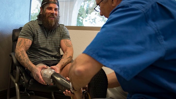 Image of Retired U.S. Army Sgt. Derek Weida jokes with a physician during his prosthetic leg fitting at a prosthetics clinic in Las Vegas in April 2018. .