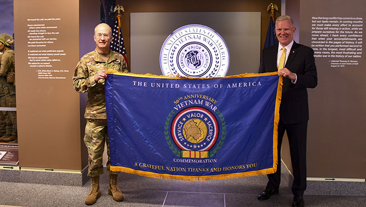 Image of U.S. Army Lt. Gen. (Dr.) Ron Place, Defense Health Agency director, receives a commemorative Vietnam War flag from Army Maj. Gen. (Retired) Peter Aylward, The United States of America Vietnam Commemoration director. (Photo: Sonia Clark, MHS Communications) .