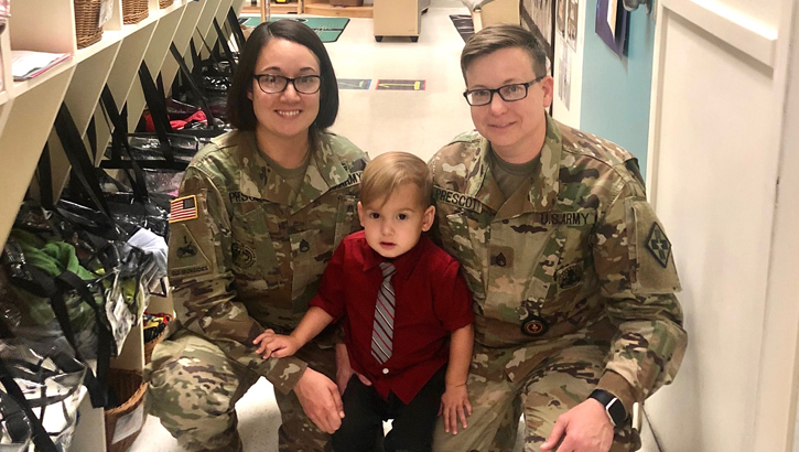 Image of Mom and Dad in military gear with their young son.
