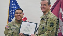2nd Lt. Jose A. Gomez, chief of pathology at Bayne-Jones Army Community Hospital, presents an Army Medical Department Regiment certificate to Pvt. 1st Class Amari Thomas during Thomas’ medical laboratory specialist graduation ceremony