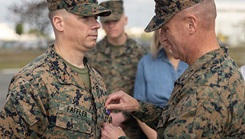 U.S. Marine Corps Brig. Gen. Kevin G. Collins, right, the commanding general of 3rd Marine Logistics Group, presents a Purple Heart to U.S. Marine Chief Warrant Officer 2 William Faffler