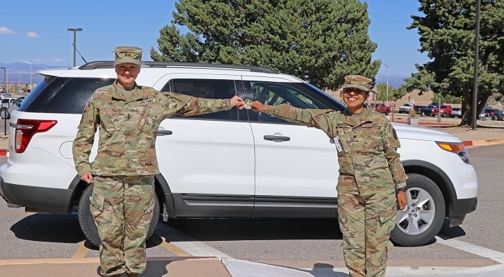Two soldiers standing in front of a car, holding a coin