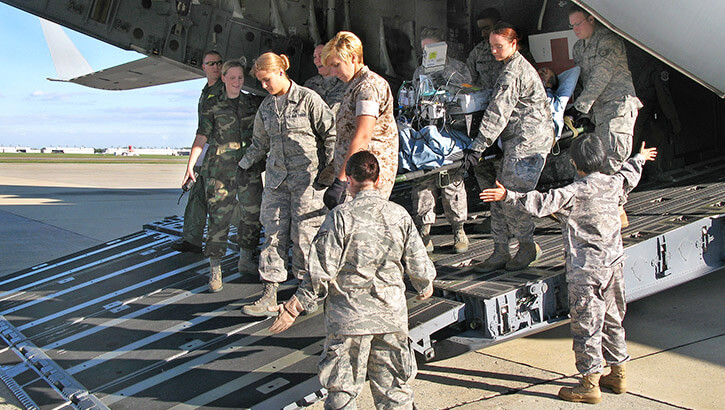 Service members transporting a severely wounded soldier