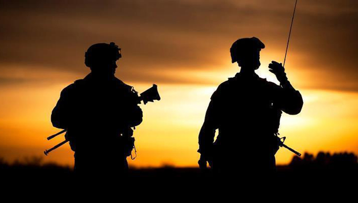 Image of Sunset light creates silhouette of two military personnel.