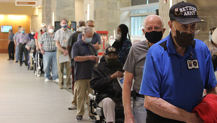 Nursing home members, wearing masks, wait in a line to get their COVID vaccine