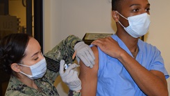 Military medical personnel administering vaccine