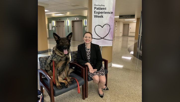 Brigid Herrick, the Chief Experience Officer (CXO) at Walter Reed National Military Medical Center, poses with one of the hospital's emotional support dogs outside of the Outpatient Phlebotomy Laboratory in Building 9 at Walter Reed in Bethesda, Maryland. (Courtesy Photo)