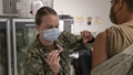 Military personnel wearing a face mask receiving the COVID-19 vaccine