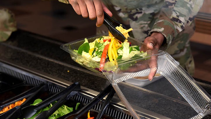 Image of A person serving himself a salad.