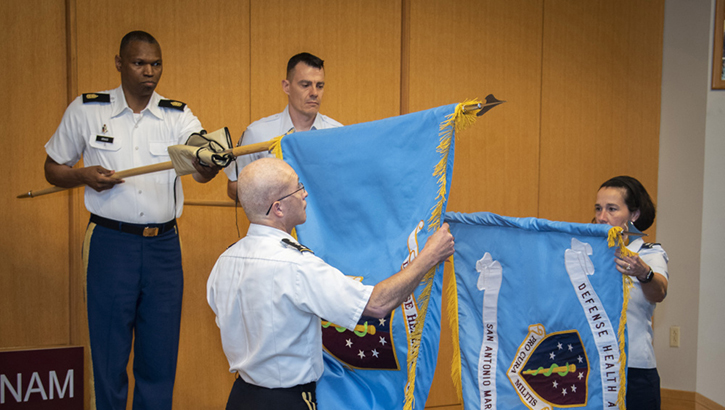 Image of Military personnel unveiling flags. Click to open a larger version of the image.