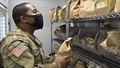 Military pharmacist, wearing a mask, looking at bags of prescriptions