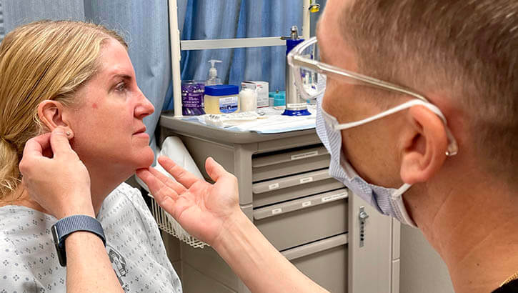 Image of U.S. Air Force Maj. Shannon Buck, a dermatologist at Landstuhl Regional Medical Center (LRMC), provides a skin cancer screening for military spouse Judy Srey on May 3, 2022. Click to open a larger version of the image.