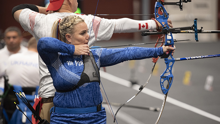 Space Force captain with raised archery bow and arrow  shown in profile competing in her first Warrior Games.