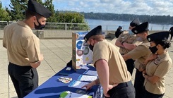 Sailors gather around a display table.