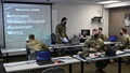 A group of military personnel wearing face mask working on laptop computers
