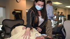 Military health personnel wearing a face mask practicing a spinal rotation technique