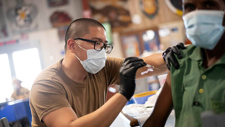 Image of Navy Petty Officer 3rd Class Jemuel Macabali, from San Diego, Calif., gives the COVID-19 vaccine to staff at Camp Lemonnier, in Djibouti, Aug. 13, 2021. . Click to open a larger version of the image.