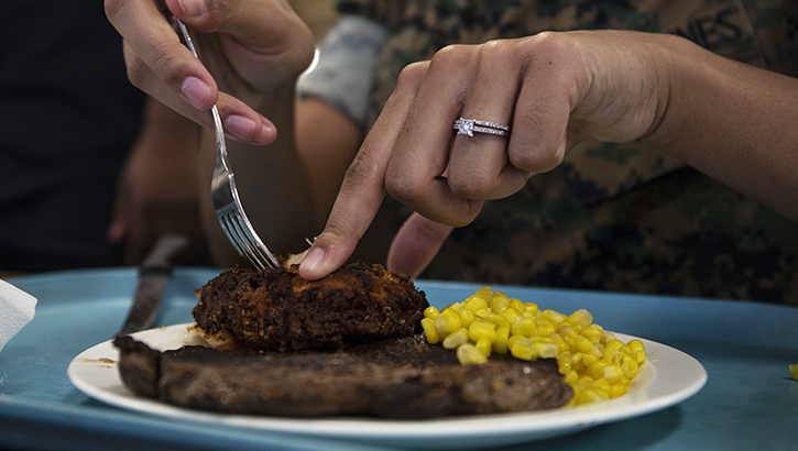 Image of Woman cutting a steak on a plate, with corn.