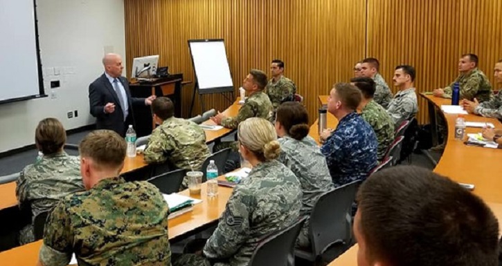 Image of Instructor at front of class, speaking to military students. Click to open a larger version of the image.